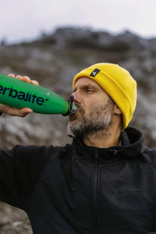 Mand drikker vand fra Herbalife-drikkedunk i naturen